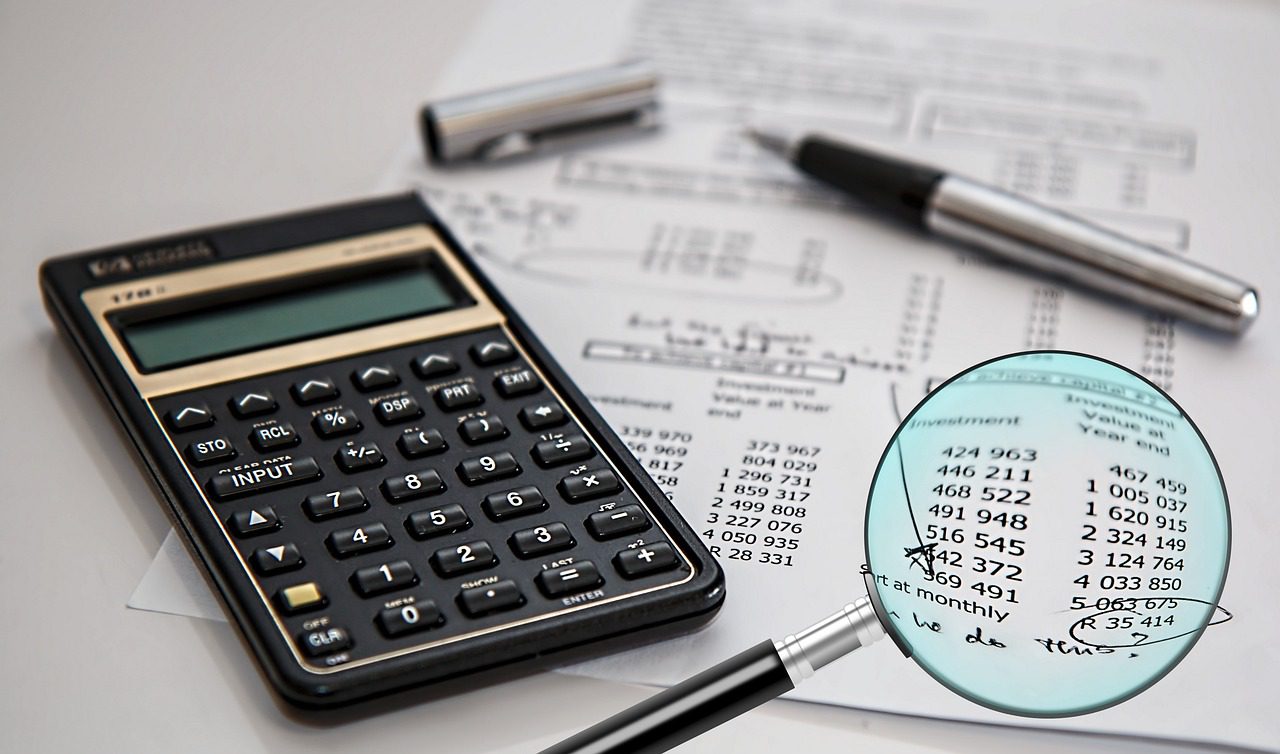 Ganancias 2025 – revision de numeros antes de presentar la declaracion jurada Calculadora, lupa y planilla de numeros sobre un escritorio para revisar la declaracion jurada de Ganancias